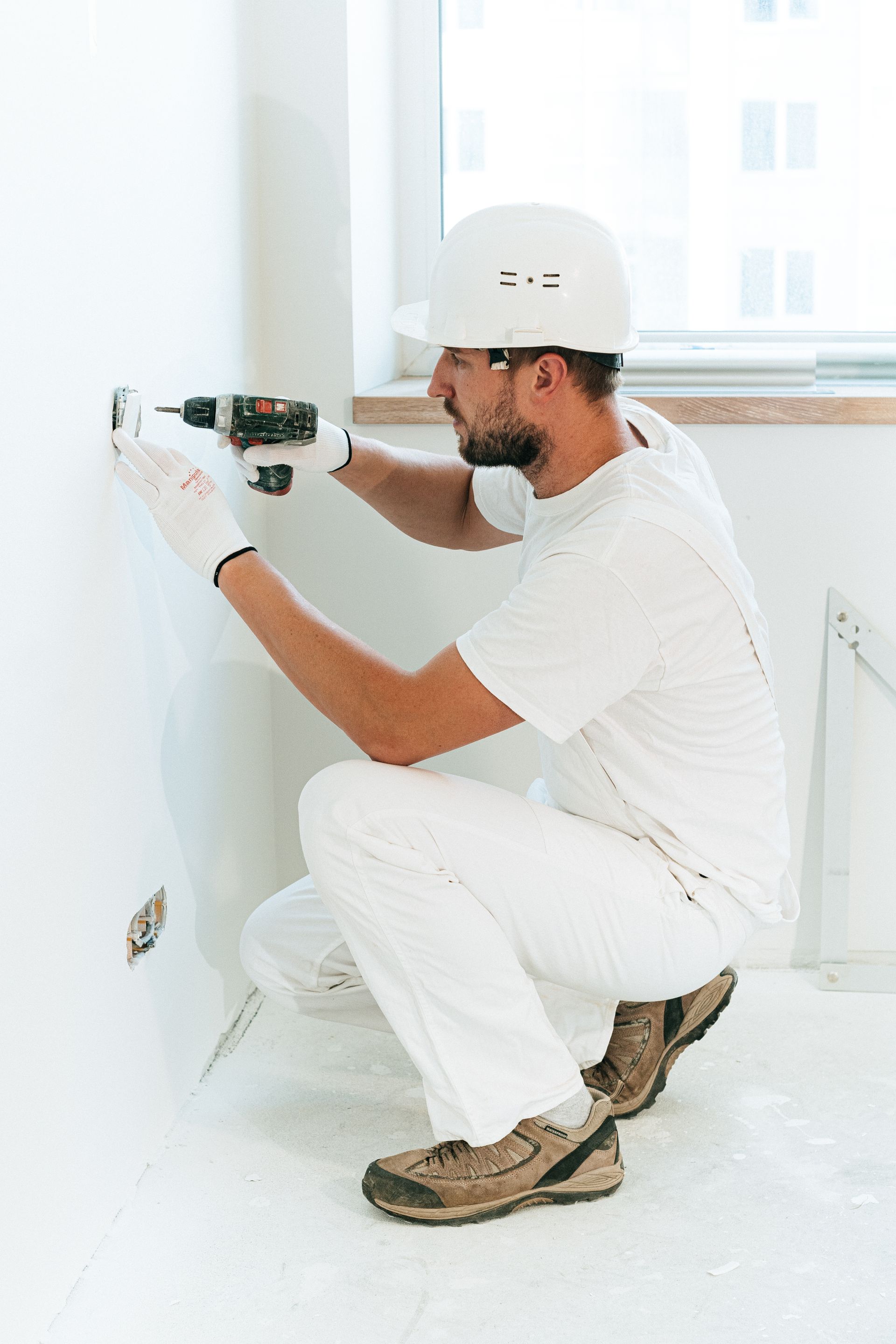 Person installing a butterfly bolt into drywall with a screwdriver
